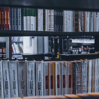 Stacks of various books placed in row on shelf in university library in daylight
